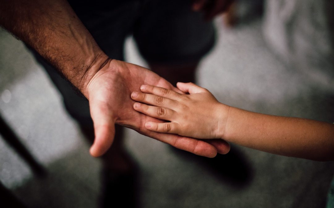 A father holding out his hand to his son's hand